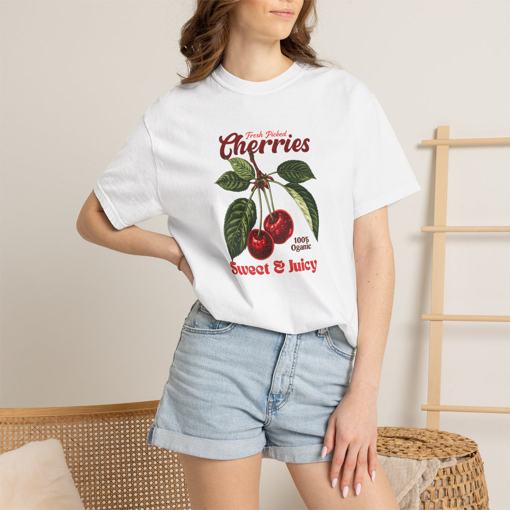 Heavyweight relaxed-fit T-shirt featuring a vintage-style botanical illustration of red cherries with green leaves and retro red script reading "Fresh Picked Cherries" and "Sweet & Juicy" on a plain background — Studio DeLuz graphic tee.