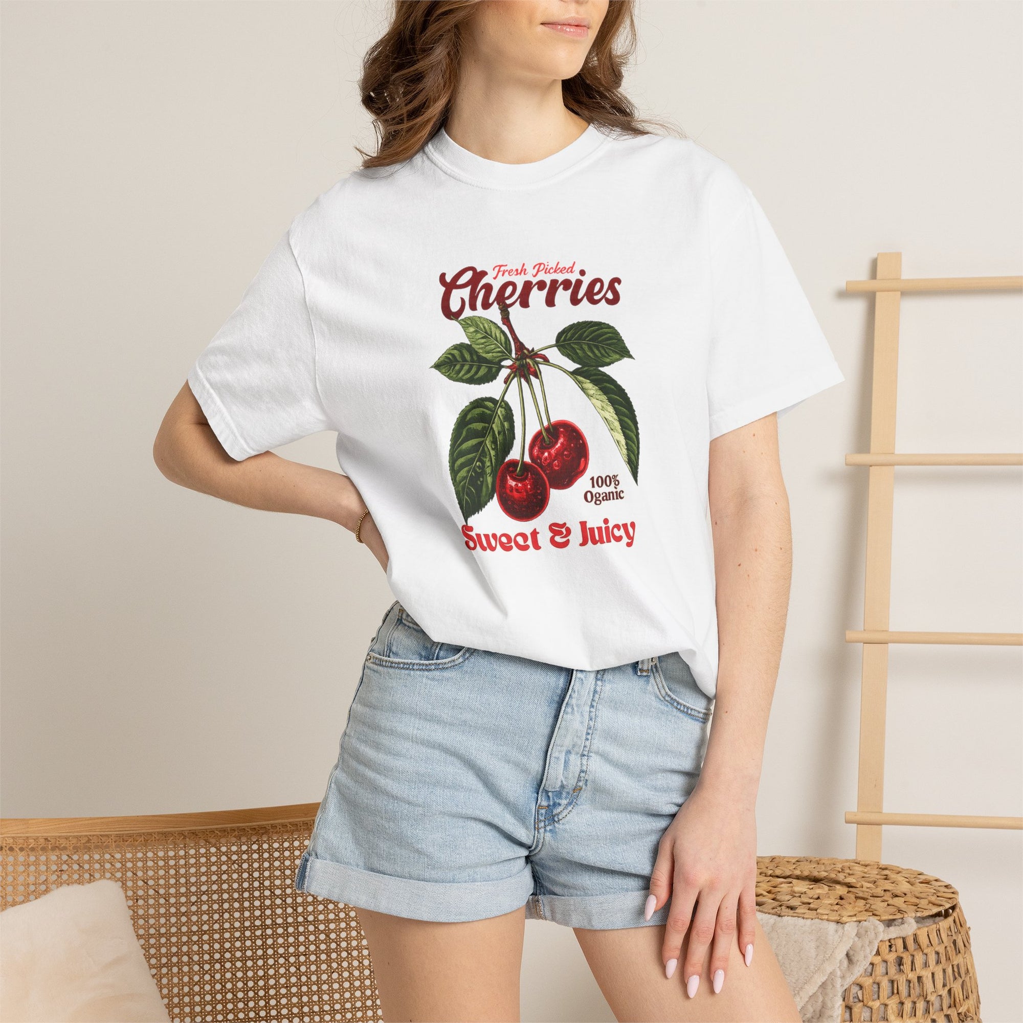 Heavyweight relaxed-fit T-shirt featuring a vintage-style botanical illustration of red cherries with green leaves and retro red script reading "Fresh Picked Cherries" and "Sweet & Juicy" on a plain background — Studio DeLuz graphic tee.