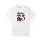 White heavyweight relaxed-fit T-shirt featuring a vintage-style botanical illustration of red cherries with green leaves and retro red script reading "Fresh Picked Cherries" and "Sweet & Juicy" on a plain background — Studio DeLuz graphic tee.