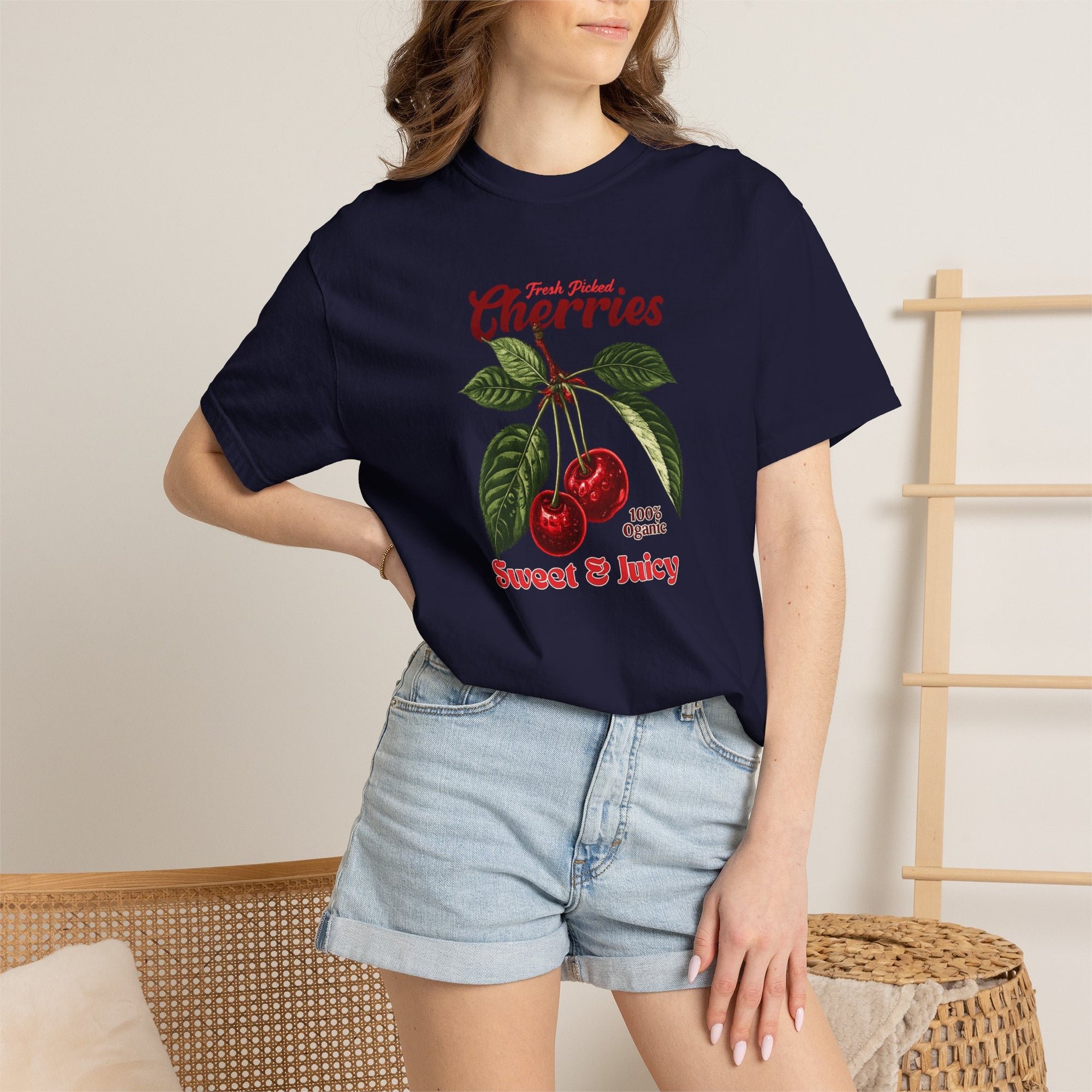 Heavyweight relaxed-fit T-shirt featuring a vintage-style botanical illustration of red cherries with green leaves and retro red script reading "Fresh Picked Cherries" and "Sweet & Juicy" on a plain background — Studio DeLuz graphic tee.