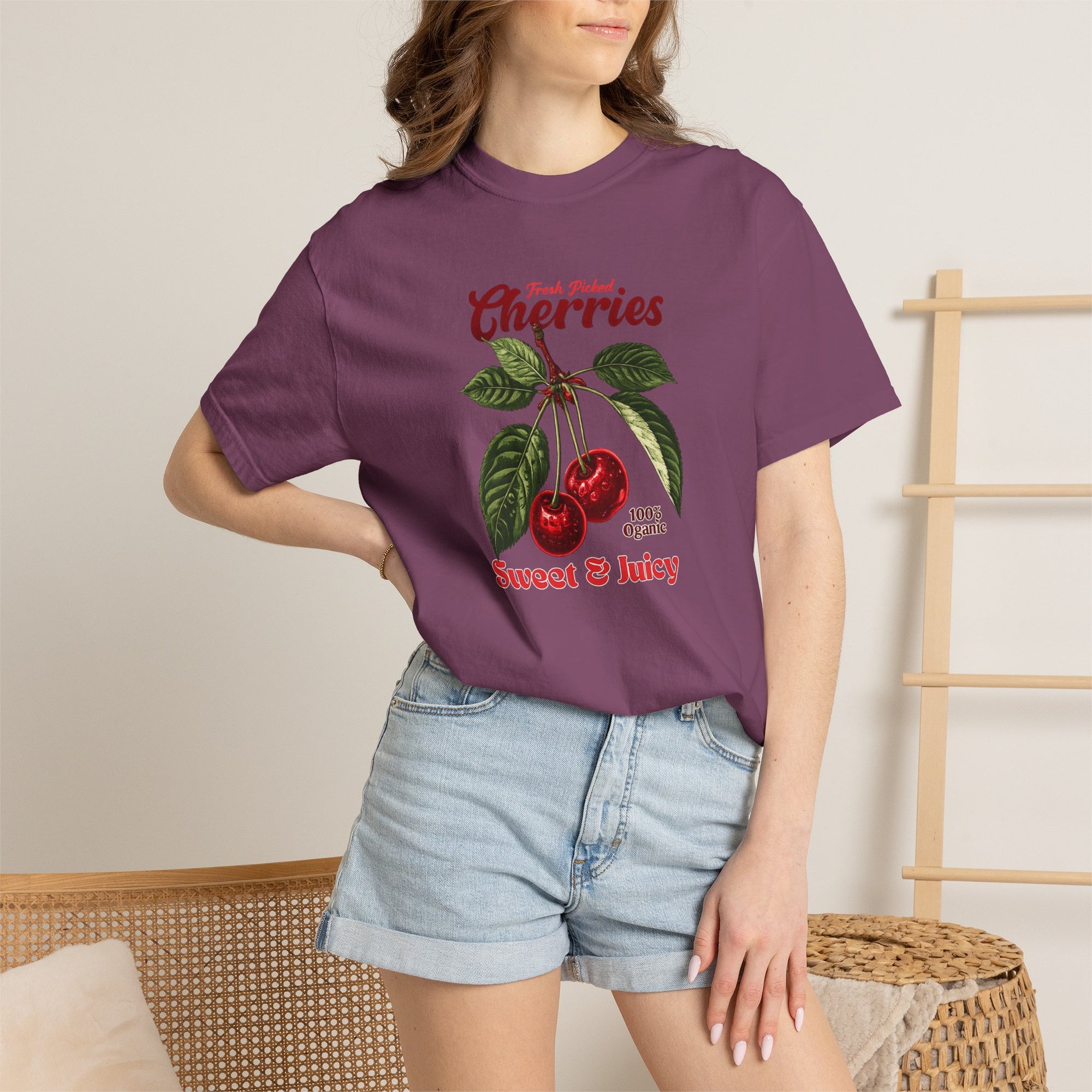 Heavyweight relaxed-fit T-shirt featuring a vintage-style botanical illustration of red cherries with green leaves and retro red script reading "Fresh Picked Cherries" and "Sweet & Juicy" on a plain background — Studio DeLuz graphic tee.