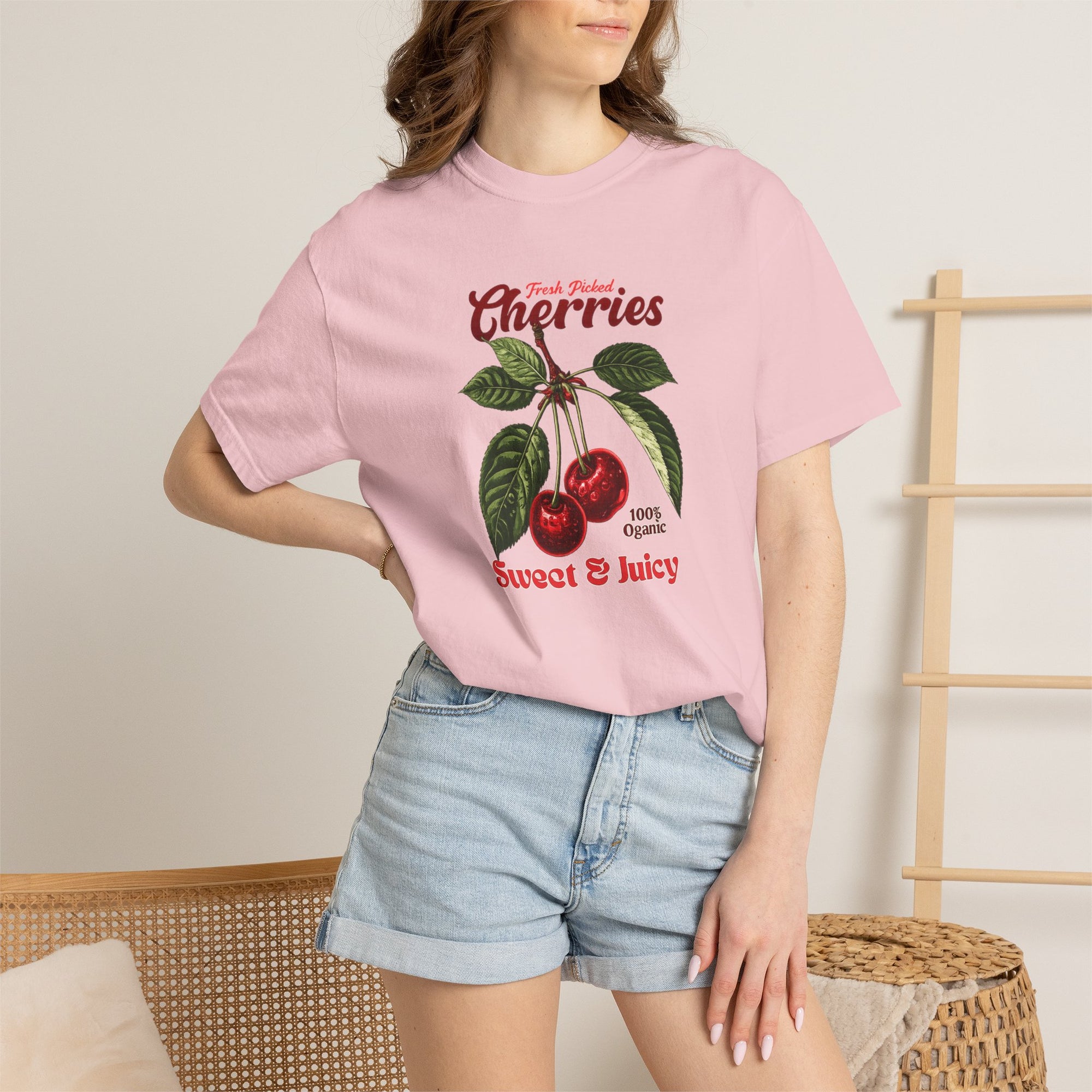 Heavyweight relaxed-fit T-shirt featuring a vintage-style botanical illustration of red cherries with green leaves and retro red script reading "Fresh Picked Cherries" and "Sweet & Juicy" on a plain background — Studio DeLuz graphic tee.