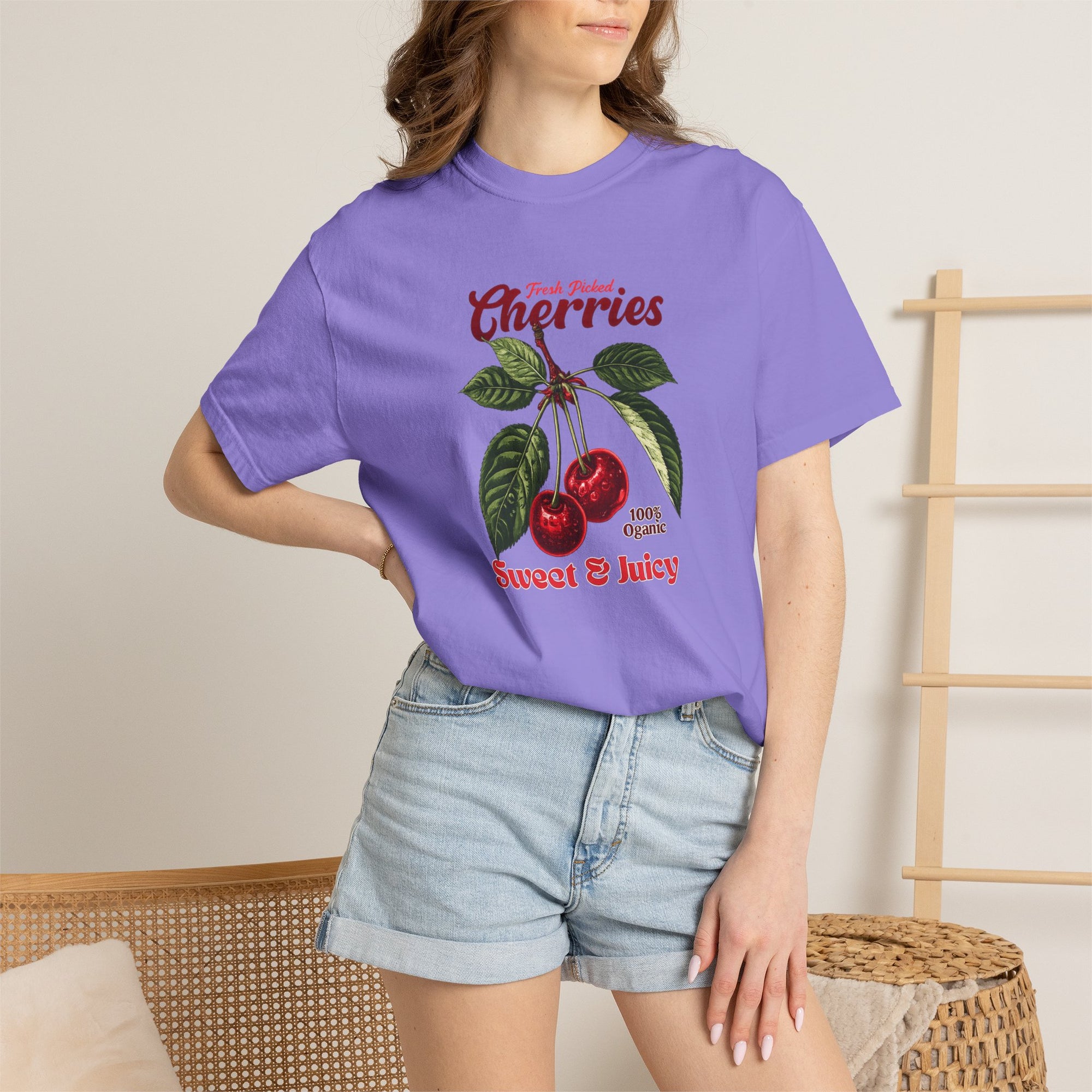 Heavyweight relaxed-fit T-shirt featuring a vintage-style botanical illustration of red cherries with green leaves and retro red script reading "Fresh Picked Cherries" and "Sweet & Juicy" on a plain background — Studio DeLuz graphic tee.