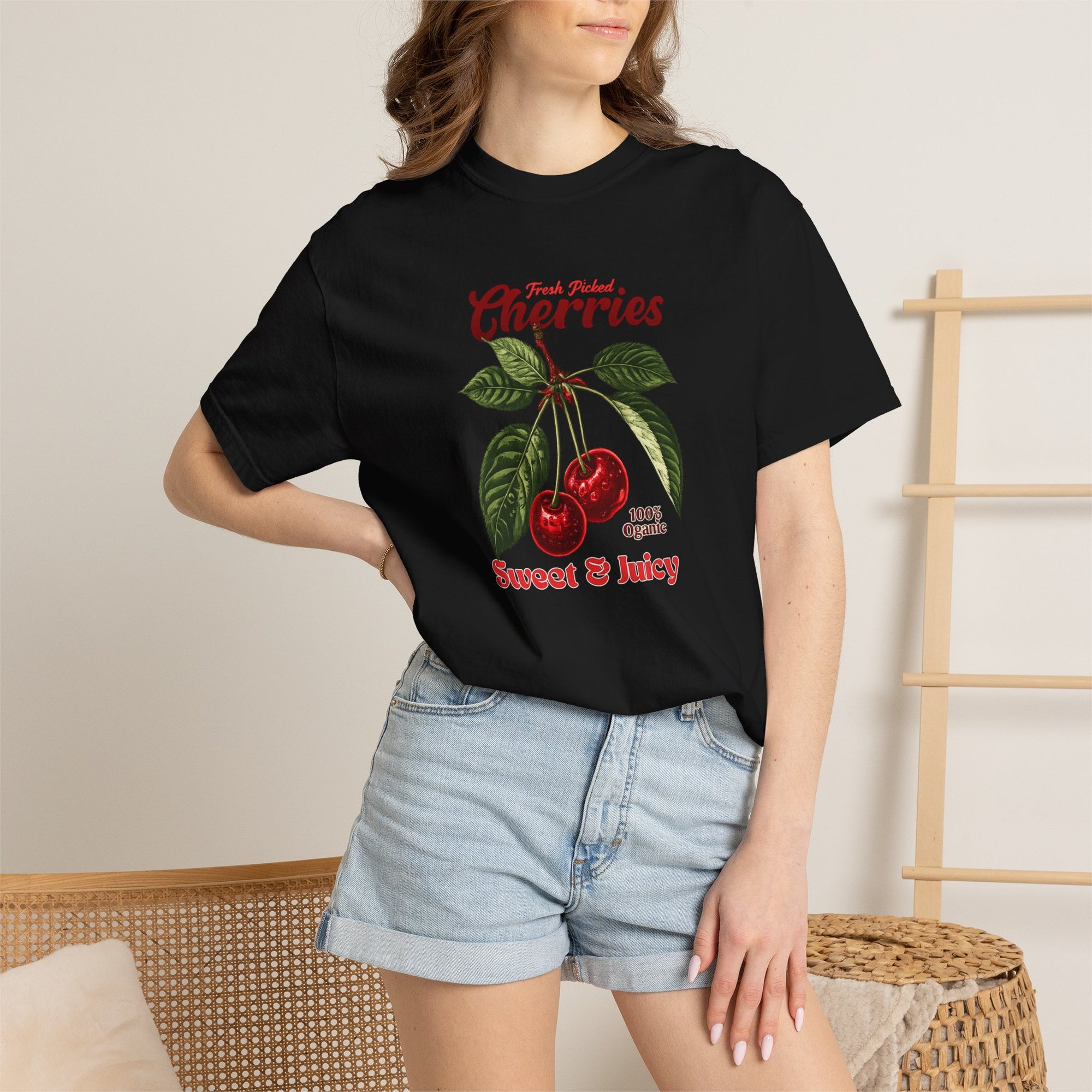 Heavyweight relaxed-fit T-shirt featuring a vintage-style botanical illustration of red cherries with green leaves and retro red script reading "Fresh Picked Cherries" and "Sweet & Juicy" on a plain background — Studio DeLuz graphic tee.