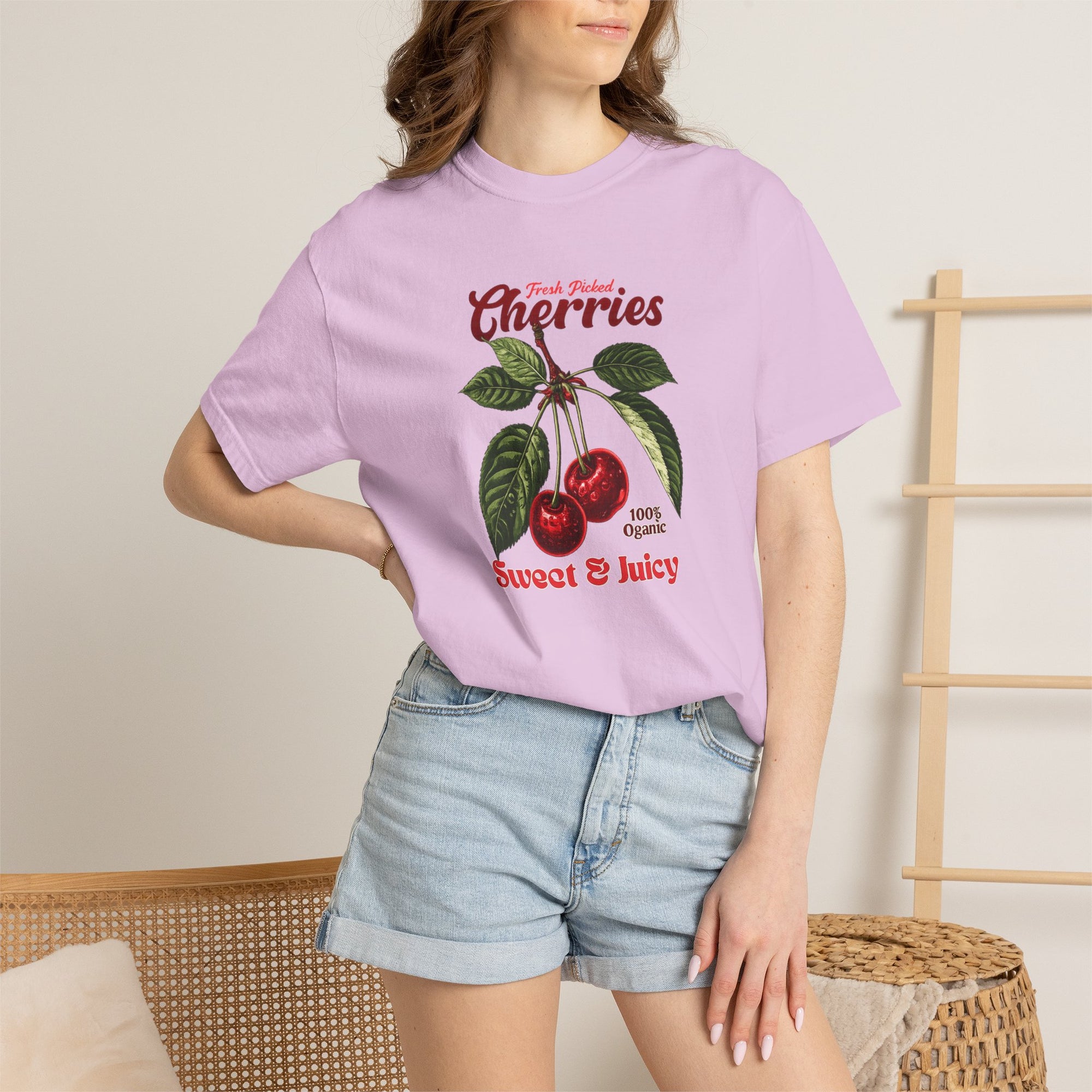 Heavyweight relaxed-fit T-shirt featuring a vintage-style botanical illustration of red cherries with green leaves and retro red script reading "Fresh Picked Cherries" and "Sweet & Juicy" on a plain background — Studio DeLuz graphic tee.